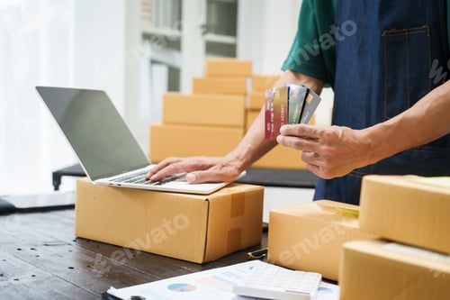 Preview: A man is working at his desk, preparing parcel boxes for shipment. He checks packs items carefully