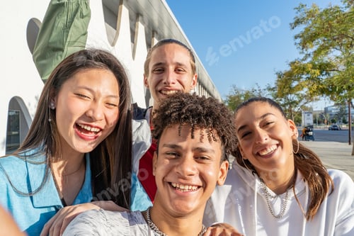 Preview: Group of happy teenage friends taking a selfie and laughing in the city street view from the camera.