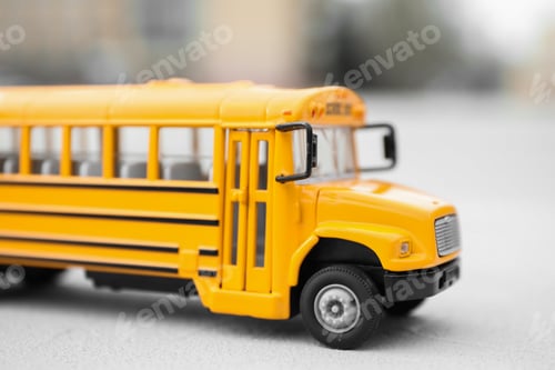 Preview: Yellow toy school bus against blurred background, closeup. Transport for students