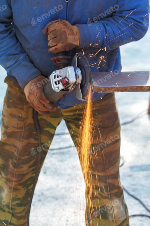 Preview: Worker cuts a metal structure with an electric flex