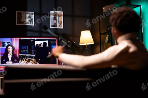 Preview: Bored man lounged on sofa, watching news broadcast while idling in living room