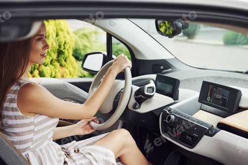 Preview: Side view. Female driver inside of modern automobile. Testing brand new car