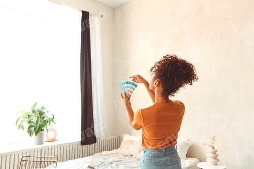 Preview: African American girl stands back to camera in middle of bedroom with paint color palette