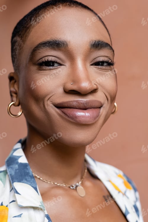 Preview: Portrait of happy short haired african american woman looking at camera outdoors
