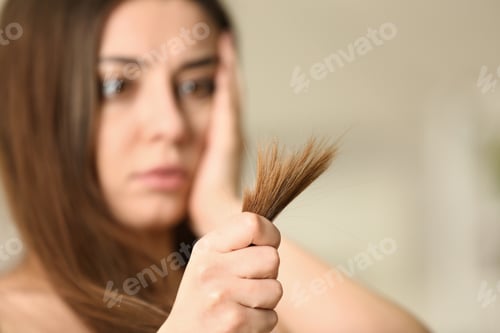 Preview: Emotional woman with damaged hair on blurred background, selective focus. Split ends