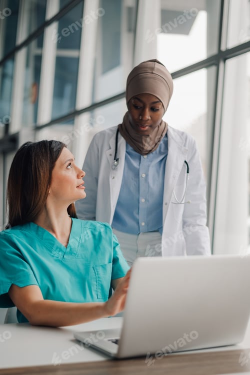 Preview: Two female doctors using laptop are discussing medical report in hospital office