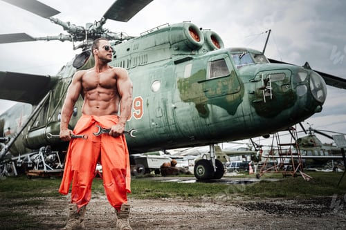 Preview: Muscular macho holding instrument in background of helicopter