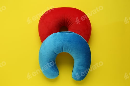 Preview: Colorful travel pillows on yellow background, top view