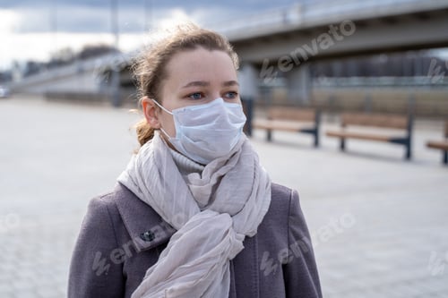 Preview: portrait young European woman in protective disposable medical mask in deserted city street outdoor