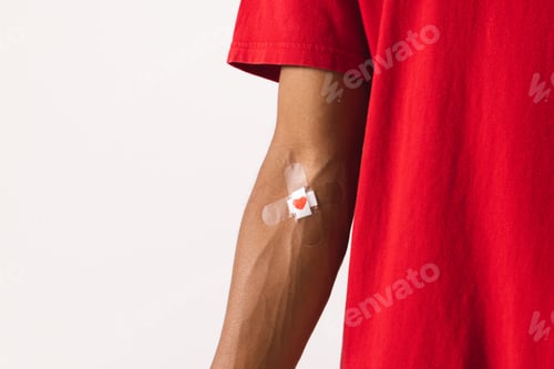 Preview: Midsection of biracial man with heart sticking plaster on arm, on white background with copy space