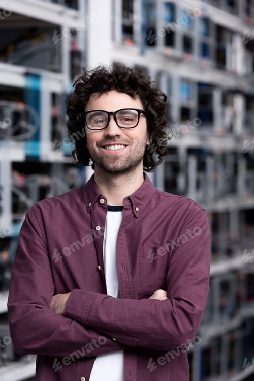Preview: young computer engineer with crossed arms at cryptocurrency mining farm