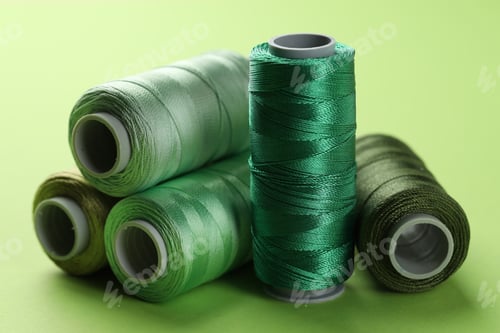 Preview: Spools of sewing threads on light green background, closeup
