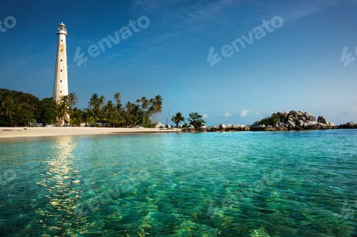 Preview: White lighthouse standing on an island in Belitung at daytime surrounded by clear blue green colored