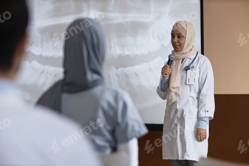 Preview: Female Dentist with Microphone Giving Presentation at Conference