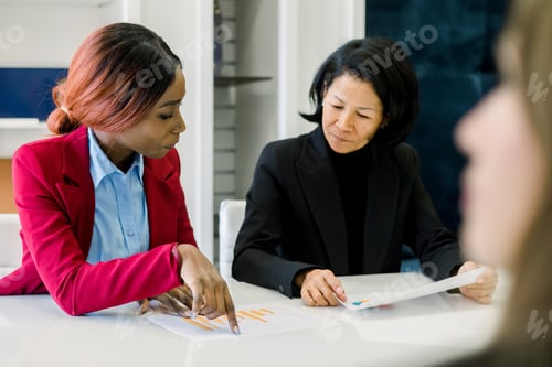 Preview: Focused multiethnic colleague working at table in office