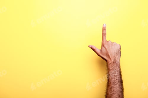 Preview: Male hand pointing up on a yellow background