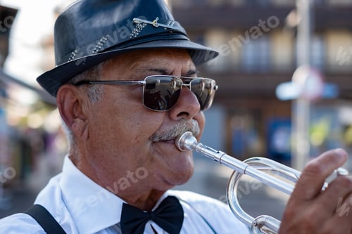 Preview: Portrait of jazz artist outdoors concert. Elderly man with black hat playing a trumpet