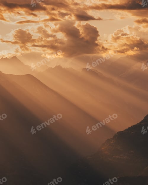 Preview: Amazing dramatic cloudscape in sunset with sun rays over misty mountains landscape
