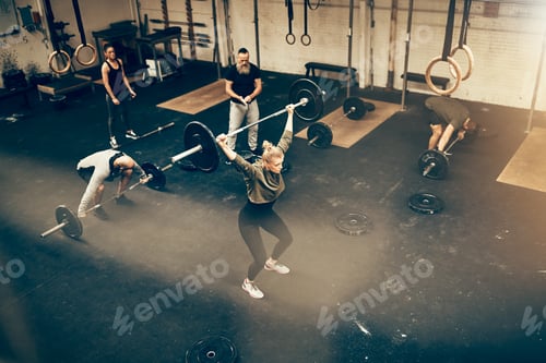 Preview: Fit people lifting weights while exercising together in a gym