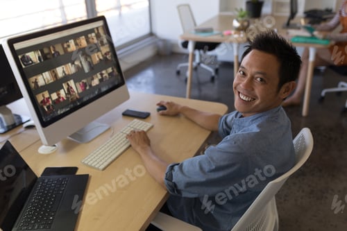 Preview: Portrait of Asian male executive working on personal computer at desk in office