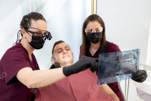 Preview: Dentists checking dental x-ray with patient in dental office during daytime