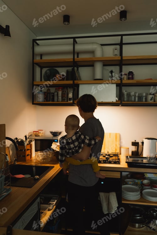 Preview: A mother holds her daughter in her arms in the kitchen.
