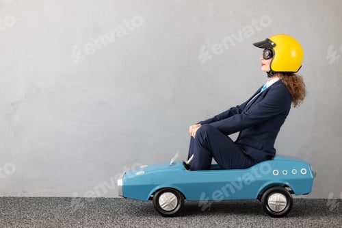 Preview: Successfull businesswoman driving toy car outdoor