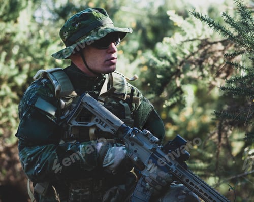 Preview: Man in Camouflage Gear with Rifle in Woods