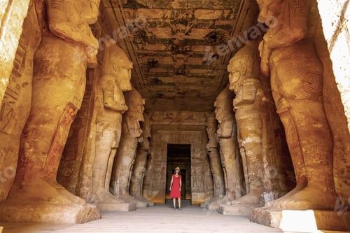 Preview: A young woman in a red dress at the Abu Simbel Temple next to the sculptures