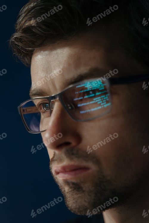 Preview: Close up of focused software engineer wearing glasses, analyzing code on his screen.
