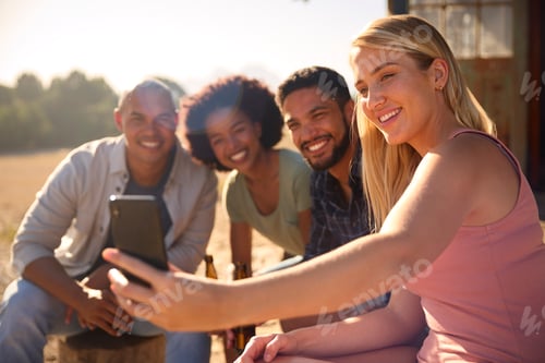 Preview: Group Of Friends On Vacation Sitting On Porch Of Countryside Cabin Drinking Beer And Taking Selfie