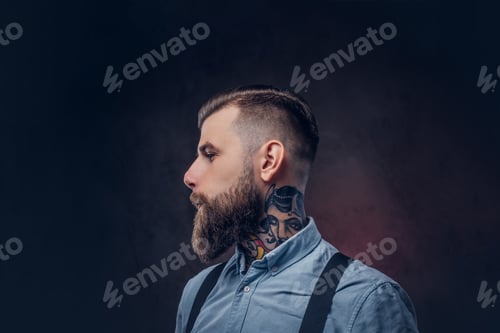 Preview: Portrait of a handsome old-fashioned hipster in a blue shirt and suspenders, posing in a studio.