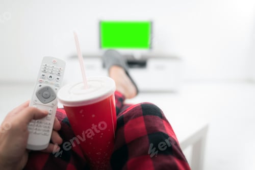 Preview: Man Drinking Soda Juice And Looking At Tv With Legs On The Table In Living Room. Chroma Key Green