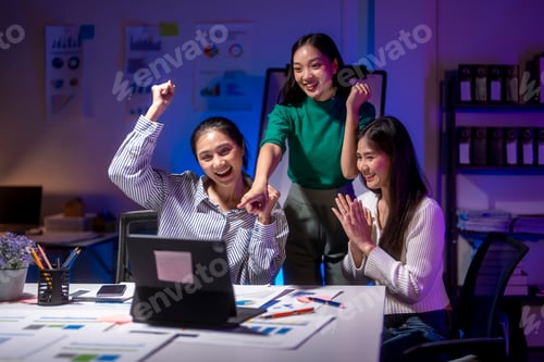 Preview: Group of young asian businesswomen celebrating success working late at night in the office
