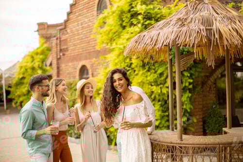 Preview: Group of young people cheering and having fun outdoors with drinks