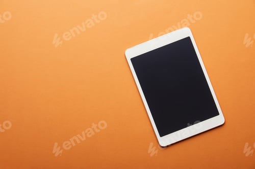 Preview: top view of digital tablet with blank screen isolated on orange