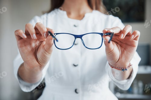 Preview: Female doctor showing the blue glasses by holding it in two hands