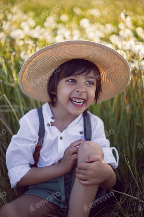 Preview: Portrait boy child in a field with dandelions at sunset. In a white shirt, hat and suspenders.