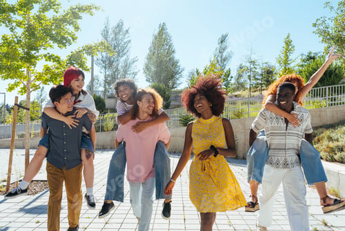 Preview: Multiethnic group of young friends meeting and having fun outdoors