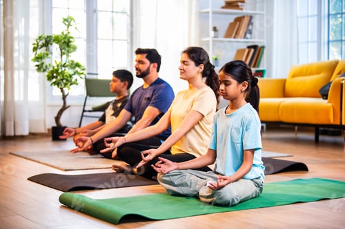 Preview: Happy Indian parents and kids practicing pranayama yoga together indoors for healthy lifestyle