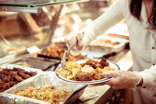 Preview: Woman wearing plastic gloves putting food on a plate - celebration and meal concept