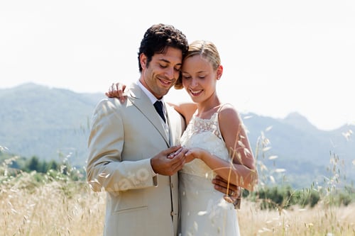 Preview: Newlyweds in field looking at wedding ring