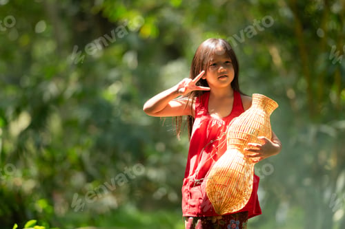Preview: Little asian girl in red dress holding fishing equipment in the forest