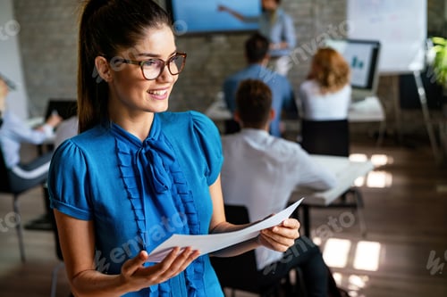 Preview: Portrait of a smiling happy young confident business woman leader in an office at team meeting.
