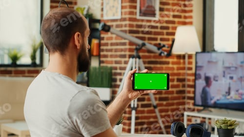 Preview: Young entrepreneur looking at greenscreen isolated display on smartphone