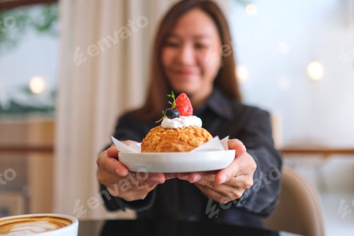 Preview: Blurred image of a woman holding and serving a plate of strawberry choux cream