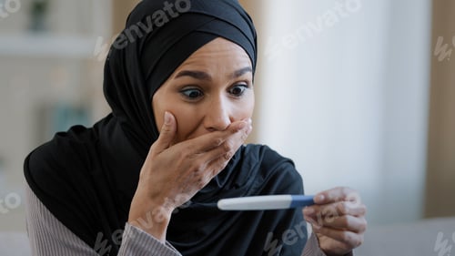 Preview: Joyful islamic young woman in hijab smiling happily holding pregnancy test excited pregnant lady