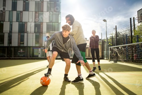 Preview: Group of adults playing football on urban football pitch