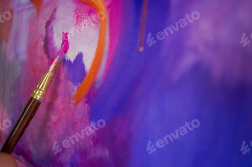 Preview: Close-up of a girl artist with a brush applying oil paint to painting standing on easel