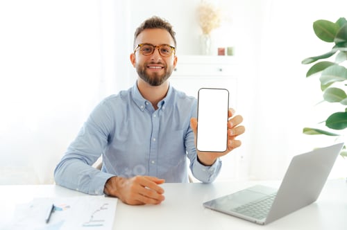 Preview: Positive successful businessman with glasses sitting at a desk in the office and showing a